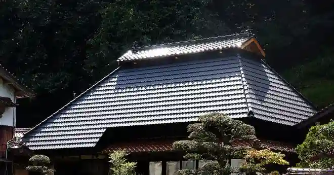 傷んだ茅葺屋根を保護するため金属屋根を上に被せる工事