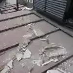 穴が空いたトタン屋根と崩れて落下した屋根ひさし